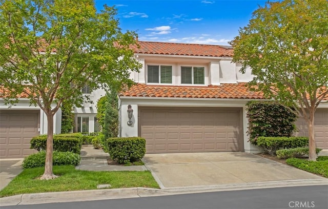 mediterranean / spanish-style home featuring concrete driveway, stucco siding, a tile roof, and a garage