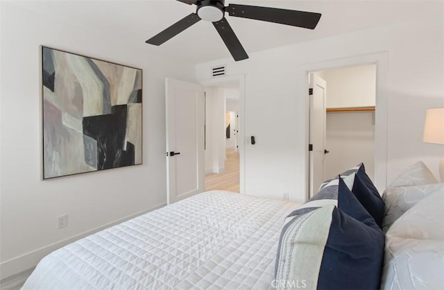 bedroom featuring baseboards, ceiling fan, visible vents, and wood finished floors