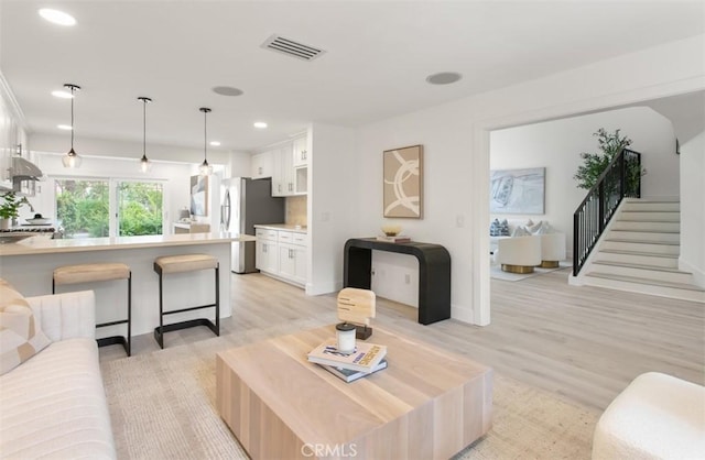 living room with light wood-style floors, visible vents, stairway, and recessed lighting