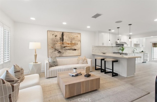 living area with light wood-style floors, baseboards, visible vents, and recessed lighting