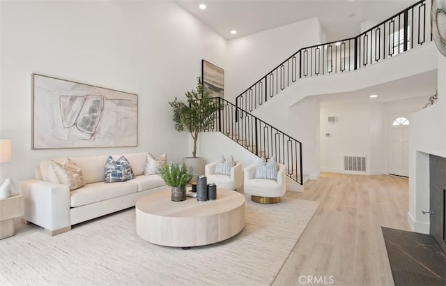 living area with wood finished floors, visible vents, recessed lighting, stairway, and a high ceiling