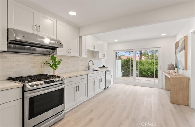 kitchen featuring extractor fan, stainless steel appliances, tasteful backsplash, light countertops, and white cabinets