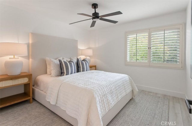 bedroom featuring ceiling fan, baseboards, and wood finished floors