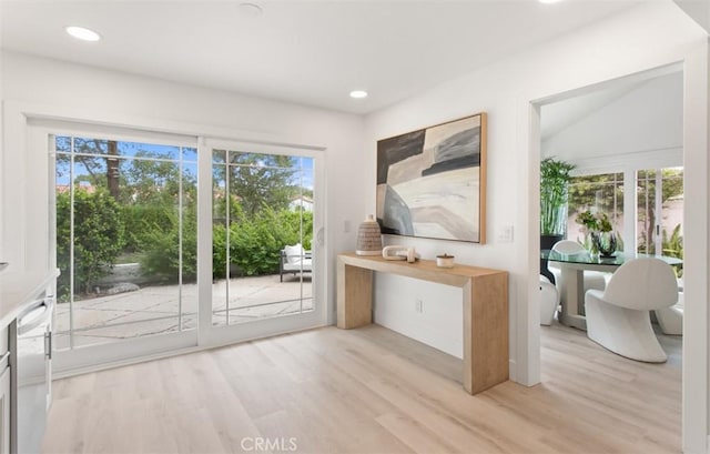 doorway featuring light wood finished floors, baseboards, and recessed lighting