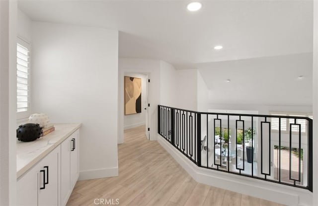 hallway featuring light wood finished floors, baseboards, and recessed lighting