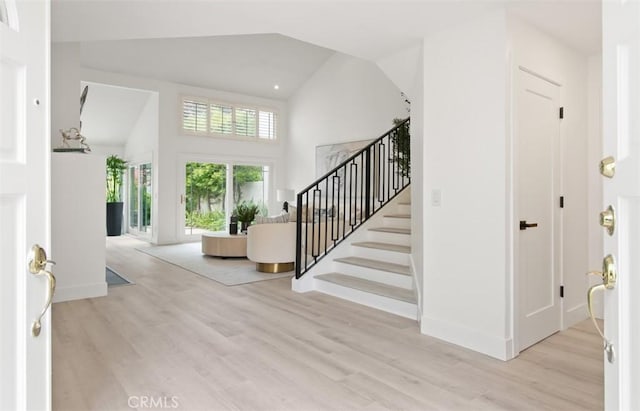 foyer with stairs, baseboards, high vaulted ceiling, and wood finished floors