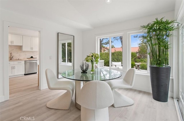 dining space featuring lofted ceiling and light wood-style floors
