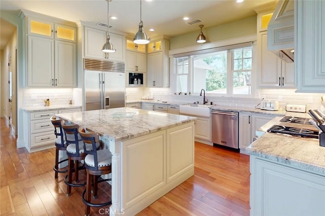 2483 Manhattan Bar Rd, Auburn, CA 95603 - kitchen featuring appliances with stainless steel finishes, a sink, a center island, decorative backsplash, and light wood-style floors