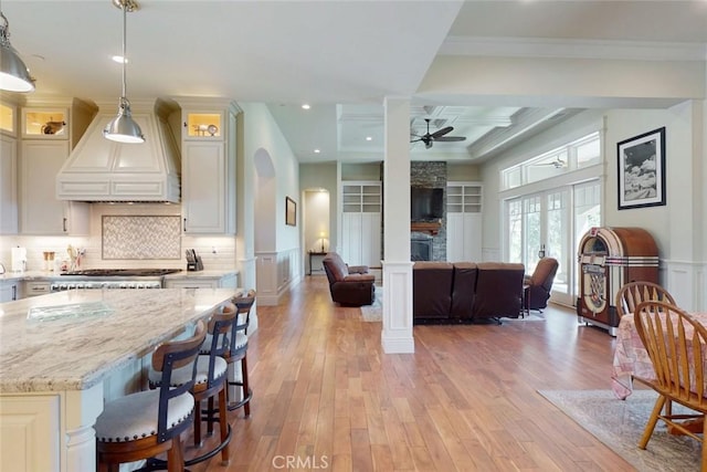 2483 Manhattan Bar Rd, Auburn, CA 95603 - kitchen featuring ceiling fan, custom range hood, light wood-style floors, light stone counters, and backsplash