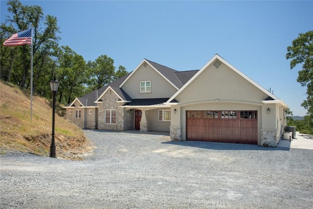 2483 Manhattan Bar Rd, Auburn, CA 95603 - view of front of home with stone siding, an attached garage, gravel driveway, a standing seam roof, and cooling unit