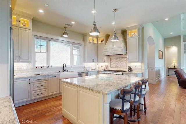 2483 Manhattan Bar Rd, Auburn, CA 95603 - kitchen with a sink, custom range hood, a kitchen island, light wood-style floors, and arched walkways