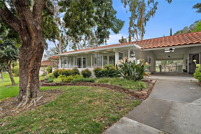 663 Via Los Altos Unit Q, Laguna Woods, CA 92637 - view of front of property featuring a tiled roof, concrete driveway, a carport, a sunroom, and a front lawn