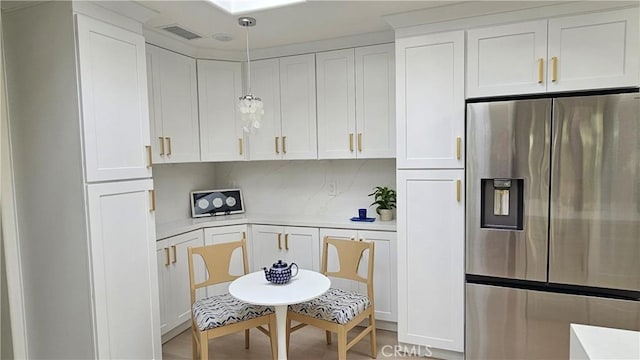 663 Via Los Altos Unit Q, Laguna Woods, CA 92637 - kitchen with stainless steel refrigerator with ice dispenser, light countertops, white cabinets, and hanging light fixtures