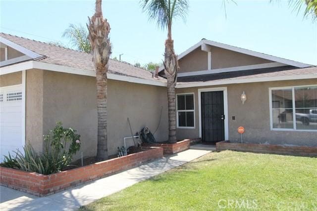 view of front of house featuring a garage, stucco siding, and a front lawn