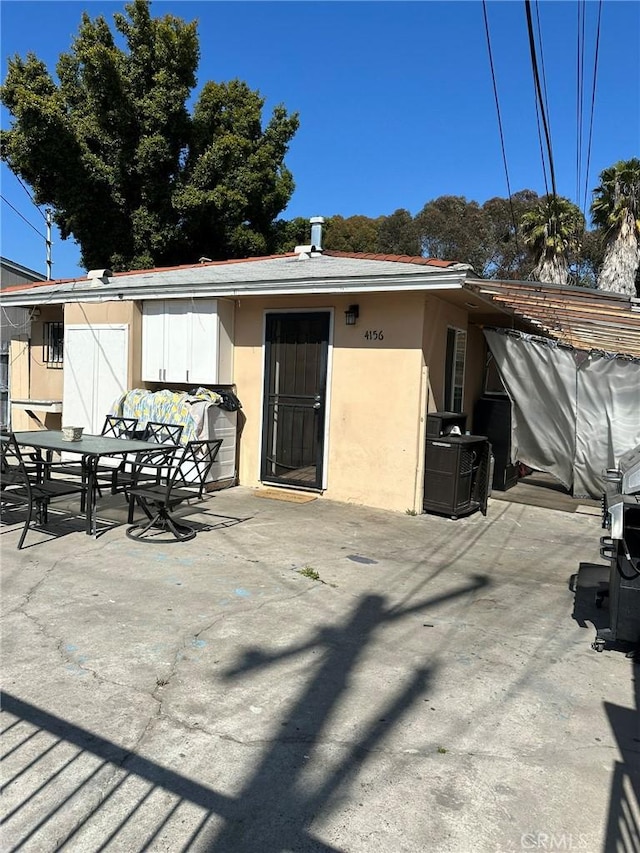back of property with outdoor dining area, a patio area, and stucco siding