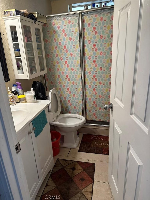bathroom with a stall shower, vanity, toilet, and tile patterned floors