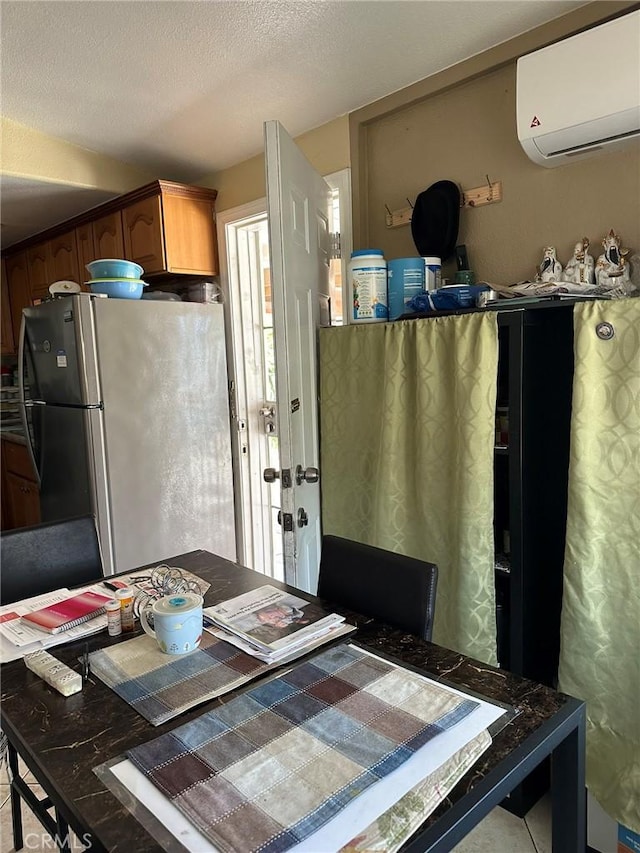 kitchen with freestanding refrigerator, a textured ceiling, and an AC wall unit