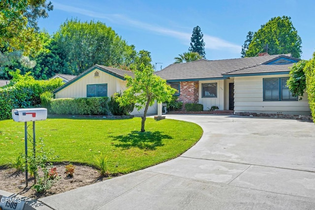 ranch-style home featuring a tiled roof, driveway, and a front yard