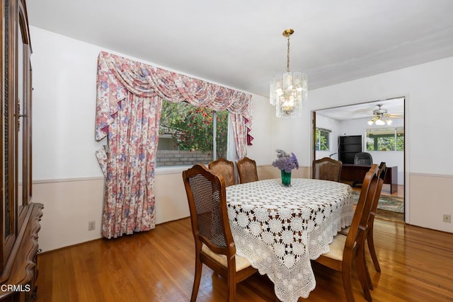 dining space with wood finished floors and ceiling fan with notable chandelier