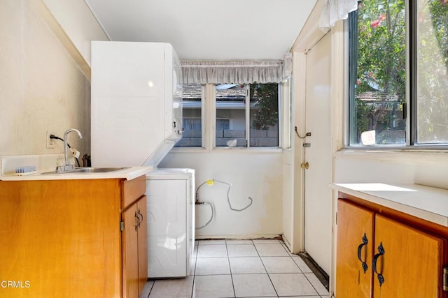 washroom with a sink, cabinet space, light tile patterned flooring, and stacked washer and dryer