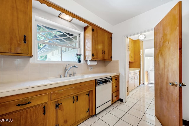 kitchen with light countertops, a sink, backsplash, dishwasher, and light tile patterned flooring