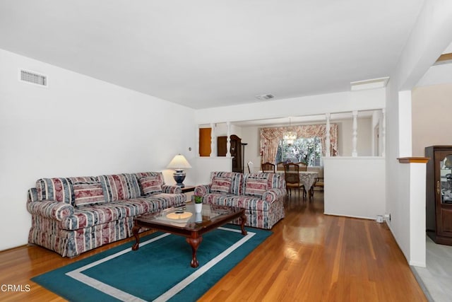 living room with a chandelier, visible vents, and wood finished floors