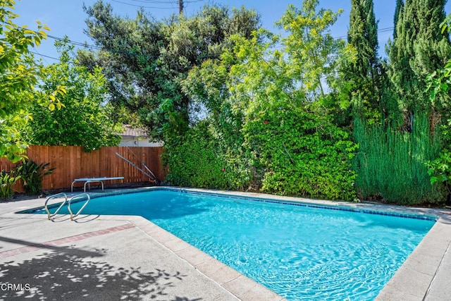 view of swimming pool with fence, a patio, a diving board, and a fenced in pool