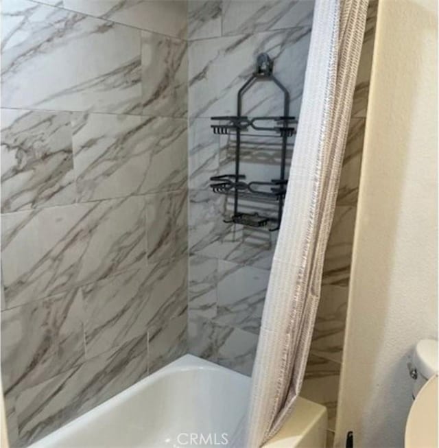 bathroom with shower / bathtub combination with curtain and toilet