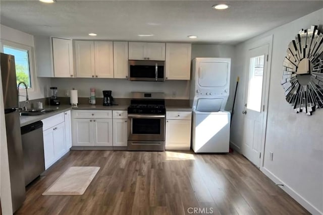 kitchen featuring a sink, dark wood finished floors, recessed lighting, stacked washer and clothes dryer, and appliances with stainless steel finishes