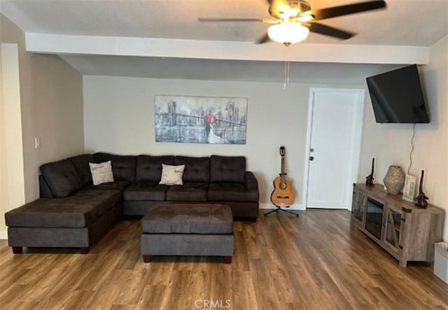 living area with baseboards, wood finished floors, a ceiling fan, and beamed ceiling