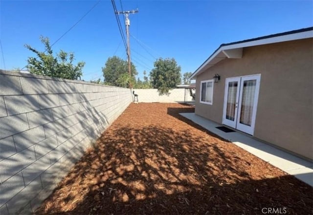 view of yard with a fenced backyard and french doors