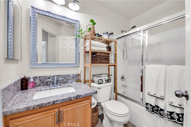 bathroom with toilet, vanity, and shower / bath combination with glass door