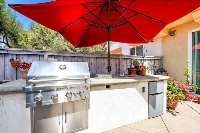view of patio / terrace featuring area for grilling, a sink, and fence