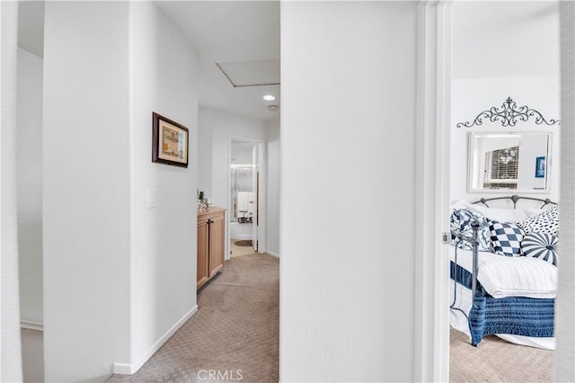 corridor with baseboards, light carpet, and attic access