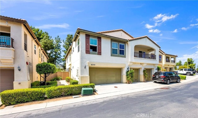 view of front of property with a tiled roof, a garage, central AC, stucco siding, and concrete driveway