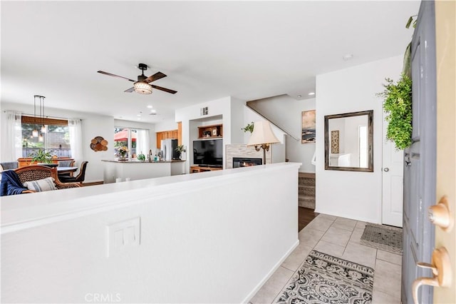 interior space featuring a ceiling fan, stairs, a glass covered fireplace, light tile patterned flooring, and recessed lighting
