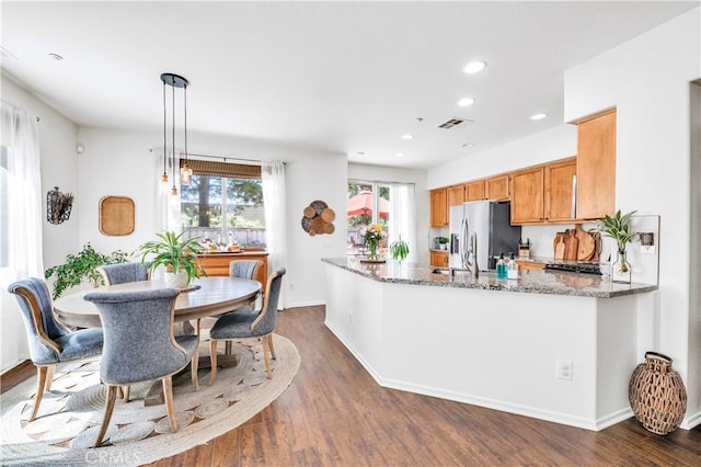 kitchen with stainless steel refrigerator with ice dispenser, visible vents, dark wood-type flooring, recessed lighting, and light stone countertops