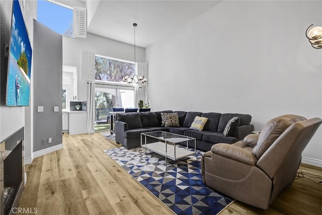 living area featuring light wood finished floors, baseboards, and a towering ceiling