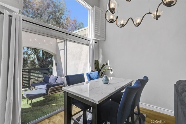 dining space with plenty of natural light, a chandelier, wood finished floors, and baseboards