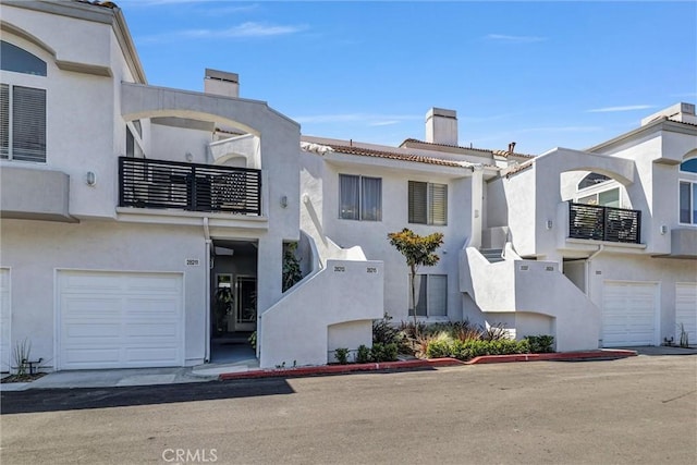 view of front of property with a chimney, a balcony, stucco siding, and a garage