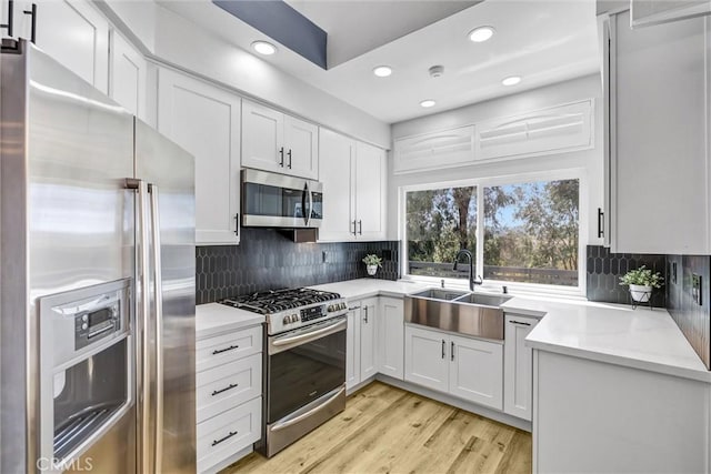 kitchen featuring a sink, tasteful backsplash, recessed lighting, white cabinets, and appliances with stainless steel finishes