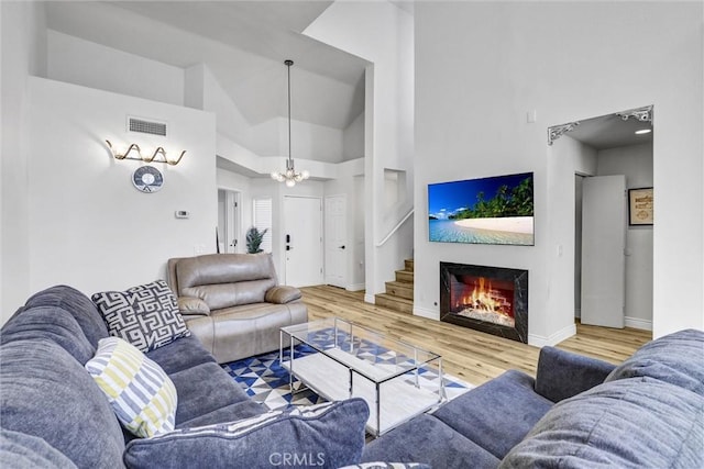 28215 Via Luis, Laguna Niguel, CA 92677 - living room featuring wood finished floors, a chandelier, a high ceiling, baseboards, and a warm lit fireplace