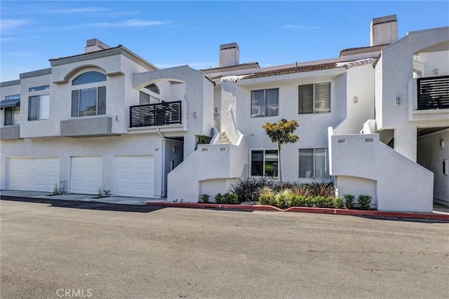 townhome / multi-family property featuring stucco siding, a chimney, and a garage