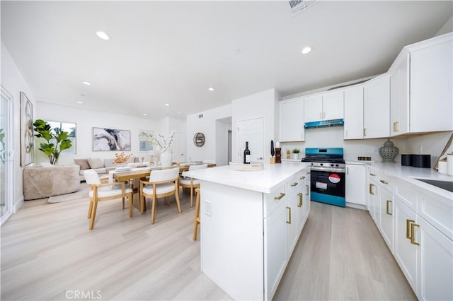 737 Lewis St, Pomona, CA 91768 - kitchen with stainless steel gas stove, visible vents, under cabinet range hood, a center island, and light wood-style floors