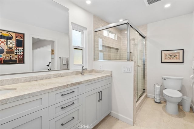 bathroom with double vanity, toilet, a stall shower, and a sink