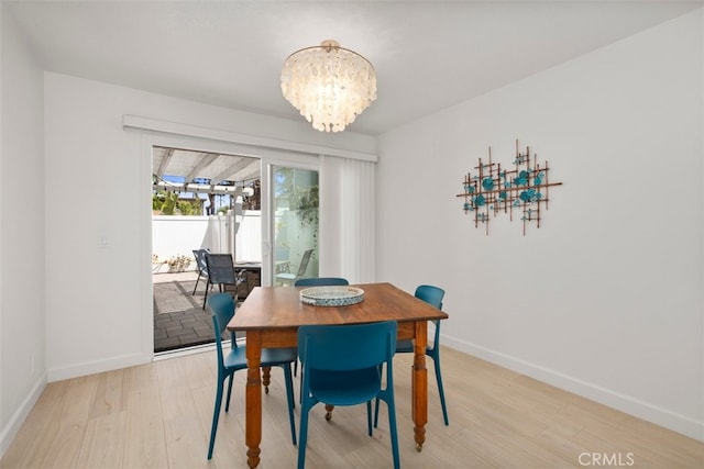 dining area featuring an inviting chandelier, light wood-style floors, and baseboards