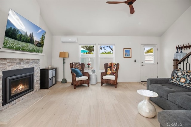 living area with vaulted ceiling, an AC wall unit, a wealth of natural light, and wood finished floors