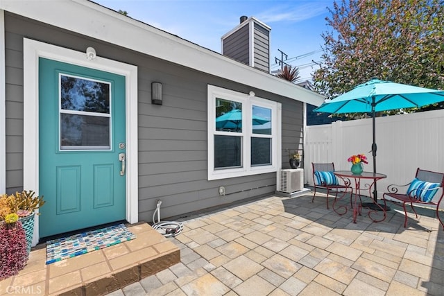 exterior space featuring a chimney, a patio area, outdoor dining area, and fence