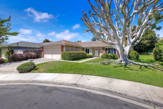 ranch-style home featuring concrete driveway, a front yard, brick siding, and a garage