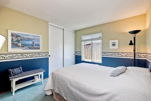 carpeted bedroom featuring a textured ceiling and a closet